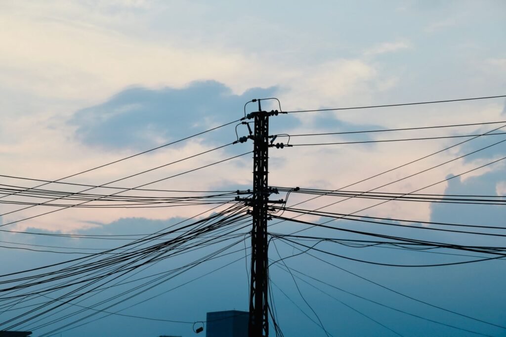 Silhouette of power lines against a dramatic sunset sky, highlighting electricity distribution.