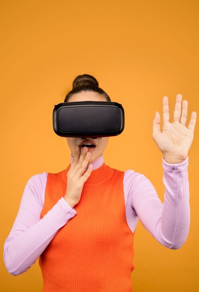 pexels photo 3761303 3761303 Woman enjoying a virtual reality experience wearing a VR headset against a vibrant orange background.