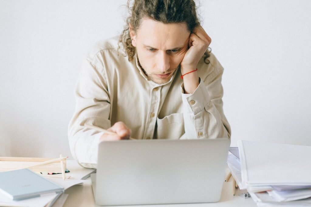 Adult man stressed at work, experiencing burnout while working on laptop at desk.