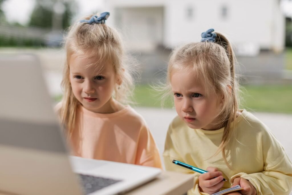 Twin girls focused on an online learning activity using a laptop.