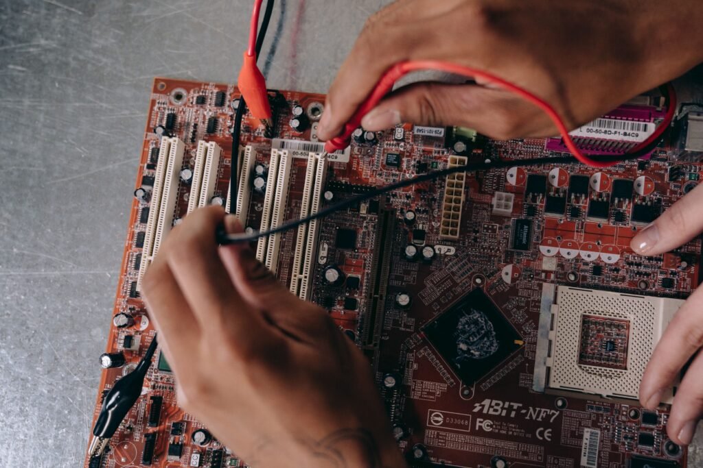 Hardware and Firmware Integration: How Embedded Products Actually Come to Life Close-up of hands working on a motherboard, showcasing electronic components and repair tools.